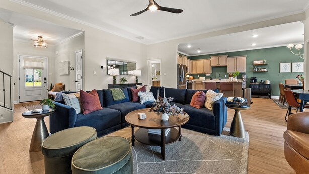 A spacious living room with a dark blue sofa, a round coffee table, and a ceiling fan.