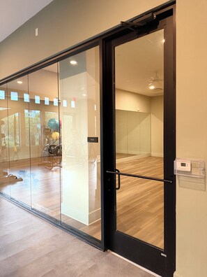 Ein modernes Interieur mit einer Glastür, die zu einem Yogaraum führt.
