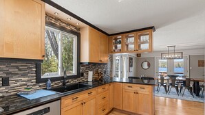 Una cucina moderna con mobili in legno, un piano di lavoro nero e vista sull'esterno.