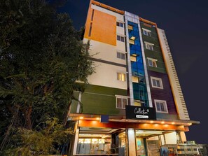 A multi-story hotel with a modern facade, a sign indicating 'Collection' and 'Company Serviced,' and a visible entrance with glass doors. - Collection O Whitefield Bangalore (Bengaluru)