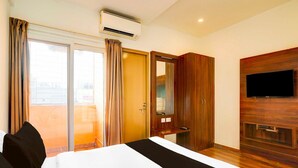 A hotel room with a bed, a TV mounted on the wall, an air conditioning unit, a sliding door, and a wooden wardrobe. - Collection O Whitefield Bangalore (Bengaluru)