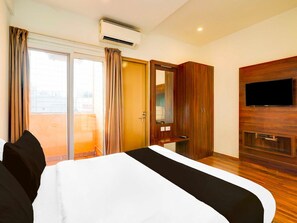 A hotel room with a bed, a TV mounted on the wall, an air conditioning unit, a sliding door, and a wooden wardrobe. - Collection O Whitefield Bangalore (Bengaluru)