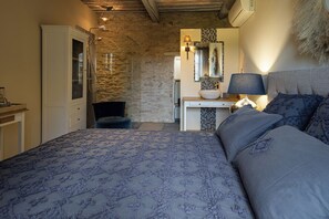 Ein Schlafzimmer mit einem Bett, einem Sessel, einem Schminktisch mit Spiegel und einer Lampe.
