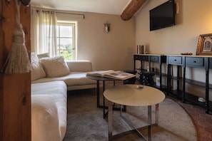 Ein gemütliches Wohnzimmer mit einer Couch, einem kleinen runden Tisch, einem Fernseher und einem Kamin.
