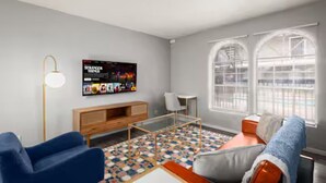 Un soggiorno moderno con un divano, un tavolino, una televisione e un tappeto decorato.