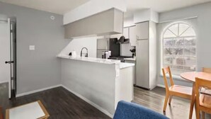 Una cucina moderna con un'isola centrale, una zona pranzo con tavolo e sedie, e un'ampia finestra che offre una vista.