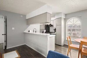 Eine moderne Küche mit einer zentralen Kochinsel, einem Essbereich mit Tisch und Stühlen sowie einem großen Fenster mit Blick.