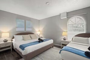Ein modernes Hotelzimmer mit einem großen Bett, Nachttischen und einem Fenster mit Jalousien.