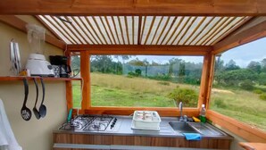 A kitchen with a gas stove, sink, and window overlooking a grassy field.