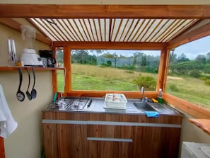 A kitchen with a gas stove, sink, and window overlooking a grassy field.