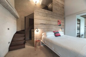 Ein Schlafzimmer mit Bett, Treppe und Holzvertäfelung an den Wänden.