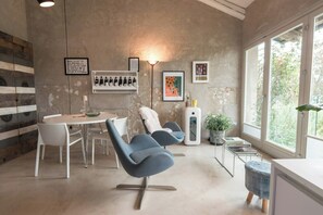 Ein modernes Interieur mit Essbereich, Sitzgelegenheiten, einem Weinkühlschrank, Kunstwerken und einem großen Fenster.