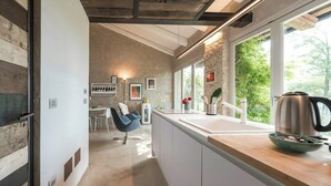 Eine moderne Küche mit einer großen Kochinsel, weißen Schränken und Blick auf Grünflächen.