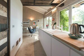 Una cocina moderna con una isla grande, muebles blancos y vistas a zonas verdes.