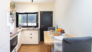 A compact kitchen with a dining area, a black door, and a window with curtains. - TenoHomes Luxury Hideaway, Buenavista (Buenavista del Norte)