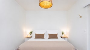A bedroom with a white bed, two bedside tables with lamps, and a woven light fixture above the bed. - TenoHomes Luxury Hideaway, Buenavista (Buenavista del Norte)