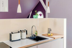 Eine Küche mit Spüle, Toaster, Kaffeemaschine und einer Topfpflanze.