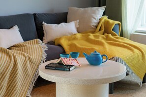 Ein runder Tisch mit Teekanne, Büchern und einer Tasse.