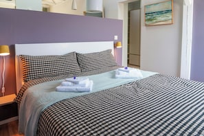 Ein ordentlich bezogenes Bett mit karierter Bettwäsche, einem Kopfteil und zwei Nachttischlampen.