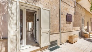 Un edificio con facciata in pietra, una porta con persiane e un piccolo fioriere a terra.