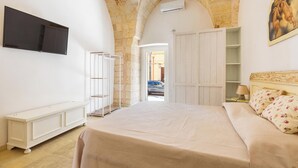 A bedroom with a bed, a TV, a wardrobe, and a painting on the wall. - La Vecchia Grotta - Trilo Comfort by BarbarHouse (Maruggio)