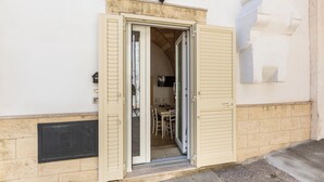 A building entrance with a door open, revealing a dining area with chairs and a table. - La Vecchia Grotta - Trilo Comfort by BarbarHouse (Maruggio)