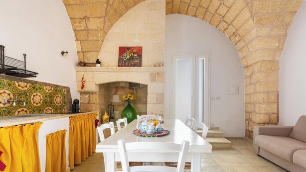 A dining area with a white table, yellow curtains, and a fireplace. - La Vecchia Grotta - Trilo Comfort by BarbarHouse (Maruggio)