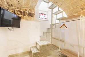 Una habitación con televisión montada en la pared, una escalera y un banco de madera.