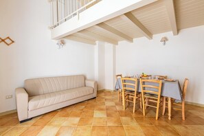 Ein Wohnzimmer mit einer Couch, einem Esstisch, Stühlen und einem Balkon.