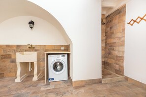 Ein Waschbereich mit Waschmaschine, Spüle und Dusche.