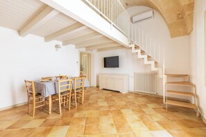 Ein Essbereich mit Tisch und Stühlen, einer Treppe, einem Fernseher und einer Heizung.