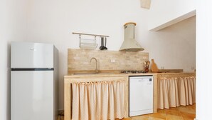 A kitchen with a refrigerator, dishwasher, and a stove. - La Vecchia Grotta - Appartamento by BarbarHouse (Maruggio)