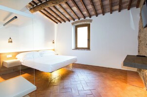 Un dormitorio con cama, mesitas de noche, ventana y techo de madera.