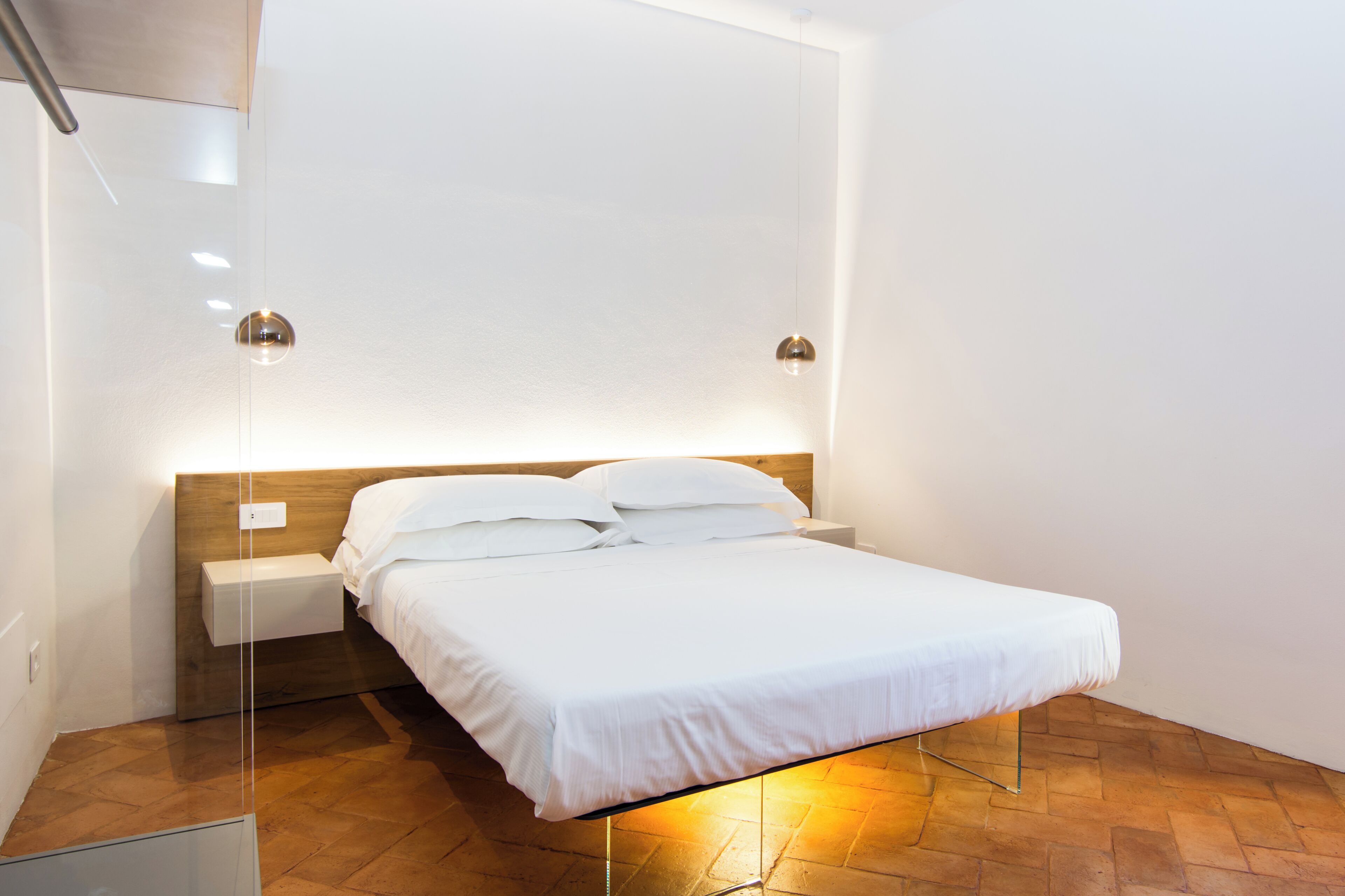 Una habitación de hotel moderna con una cama, mesitas de noche e iluminación en la pared.