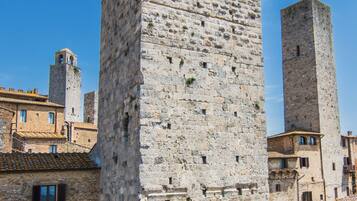 Ein historischer Steinturm mit Rundbogenfenstern und einem schmalen Durchgang.