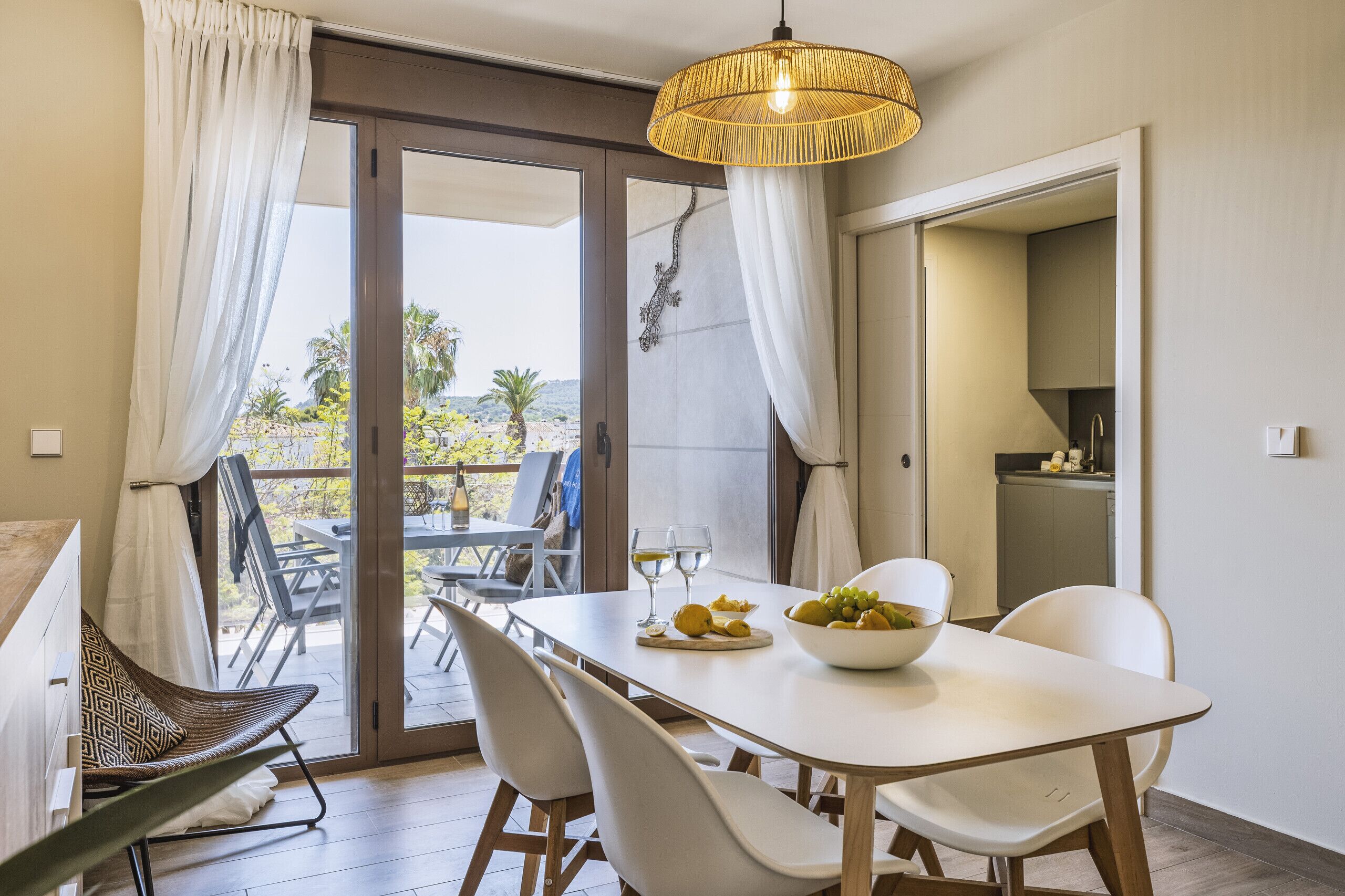 Un espace repas comprenant une table, des chaises, un luminaire suspendu et une vue sur l’extérieur.
