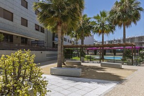 Ein Innenhof mit Palmen, einem Pool und einer überdachten Sitzgelegenheit.