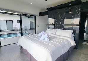 Ein modernes Schlafzimmer mit einem großen Bett, einer Glastür, die auf einen Balkon führt, und einem großen Spiegel an der Wand.