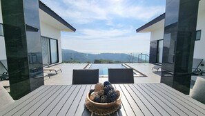 Un área de estar exterior moderna con piscina, con vistas a un paisaje montañoso.