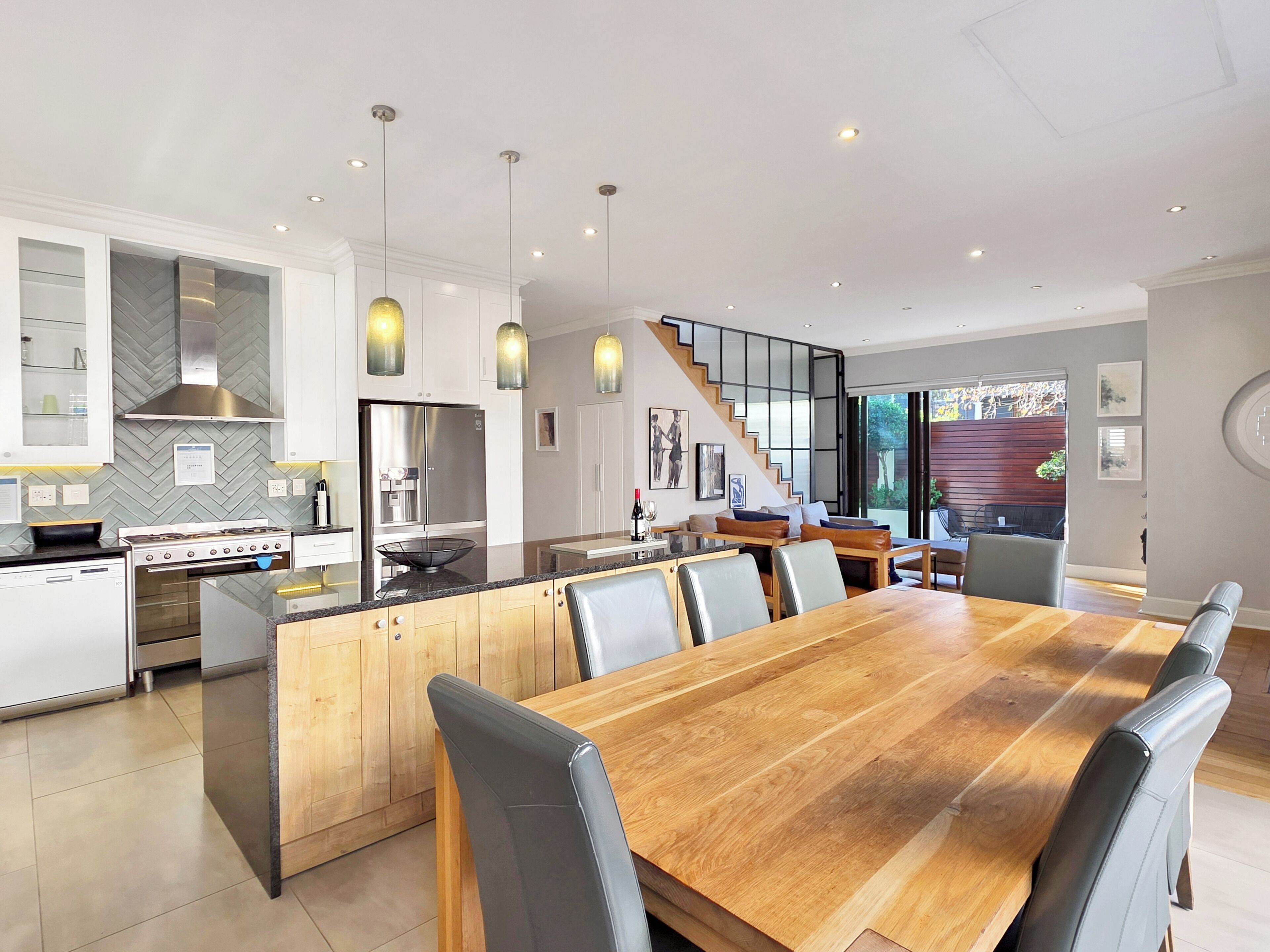 Een moderne keuken met een centraal eiland, roestvrijstalen apparatuur en hanglampen.