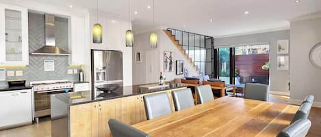 Cocina moderna con una isla central, electrodomésticos de acero inoxidable e iluminación colgante.