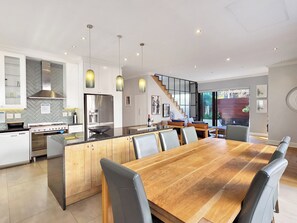 Cocina moderna con una isla central, electrodomésticos de acero inoxidable e iluminación colgante.
