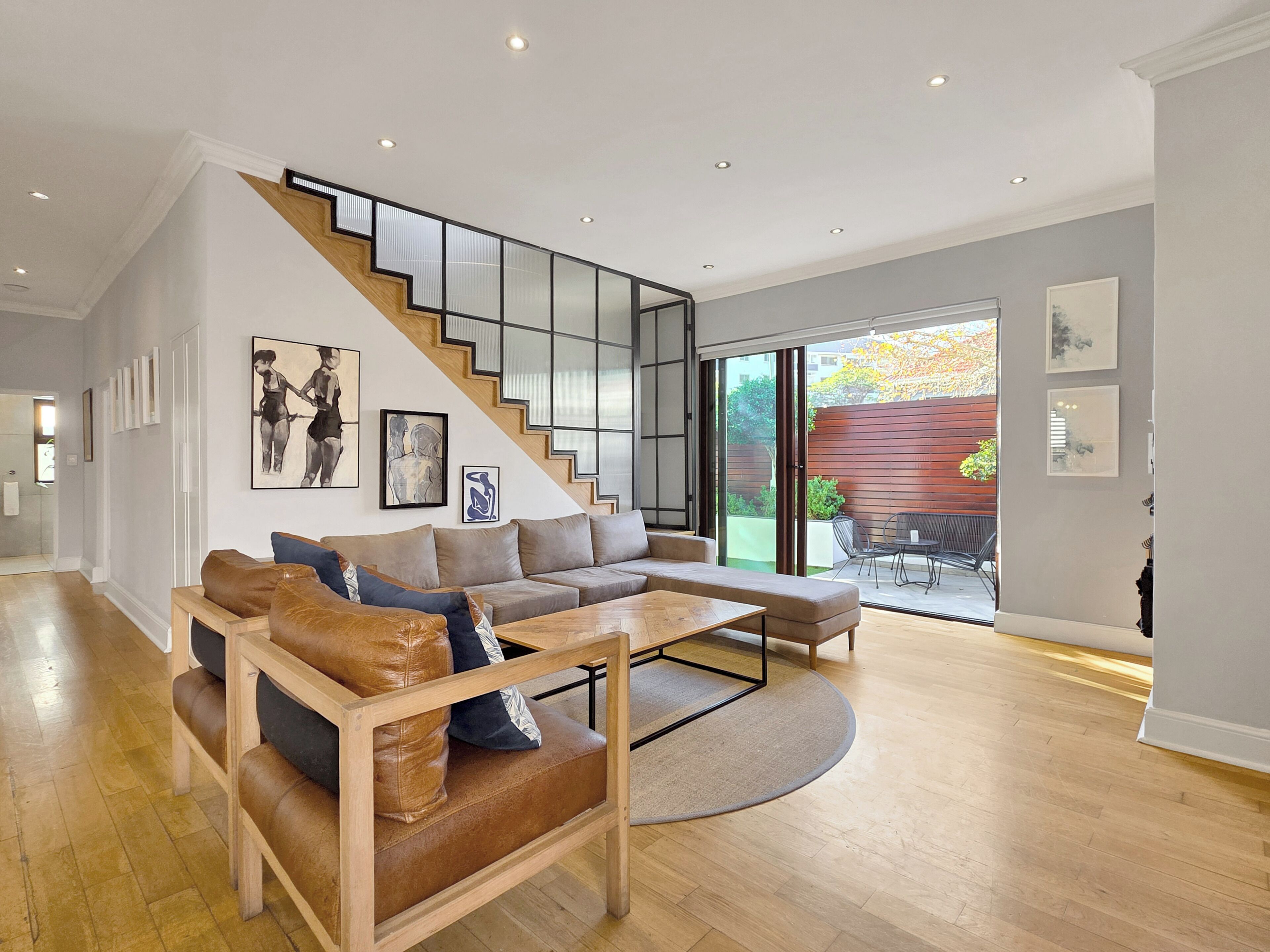 Ein modernes Wohnzimmer mit einer Holztreppe, einem Ecksofa und einem Essbereich.