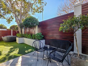 Un patio al aire libre con mesa y sillas, rodeado por una cerca de madera y follaje.