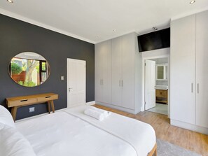 Un dormitorio con una cama, una mesita de noche, un espejo y un armario.