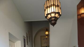 Een trap met een geruit vloertje, een landingsplaats met een blauw tapijt en een wandlamp.