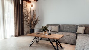 Ein modernes Wohnzimmer mit grauem Sofa, einem Holztisch und einer Blumentopf-Pflanze.