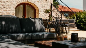 Ein Steinhaus mit großem Bogenportal, Außenbereich mit einer Couch und Stühlen sowie einem Blumentopf.
