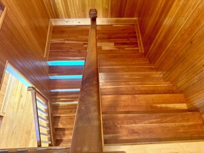 Eine Holztreppe mit Metallgeländer, Holzwänden und einem Oberlicht.