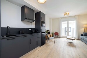 Una cocina moderna con armarios oscuros, una estufa integrada y un comedor con mesa y sillas.